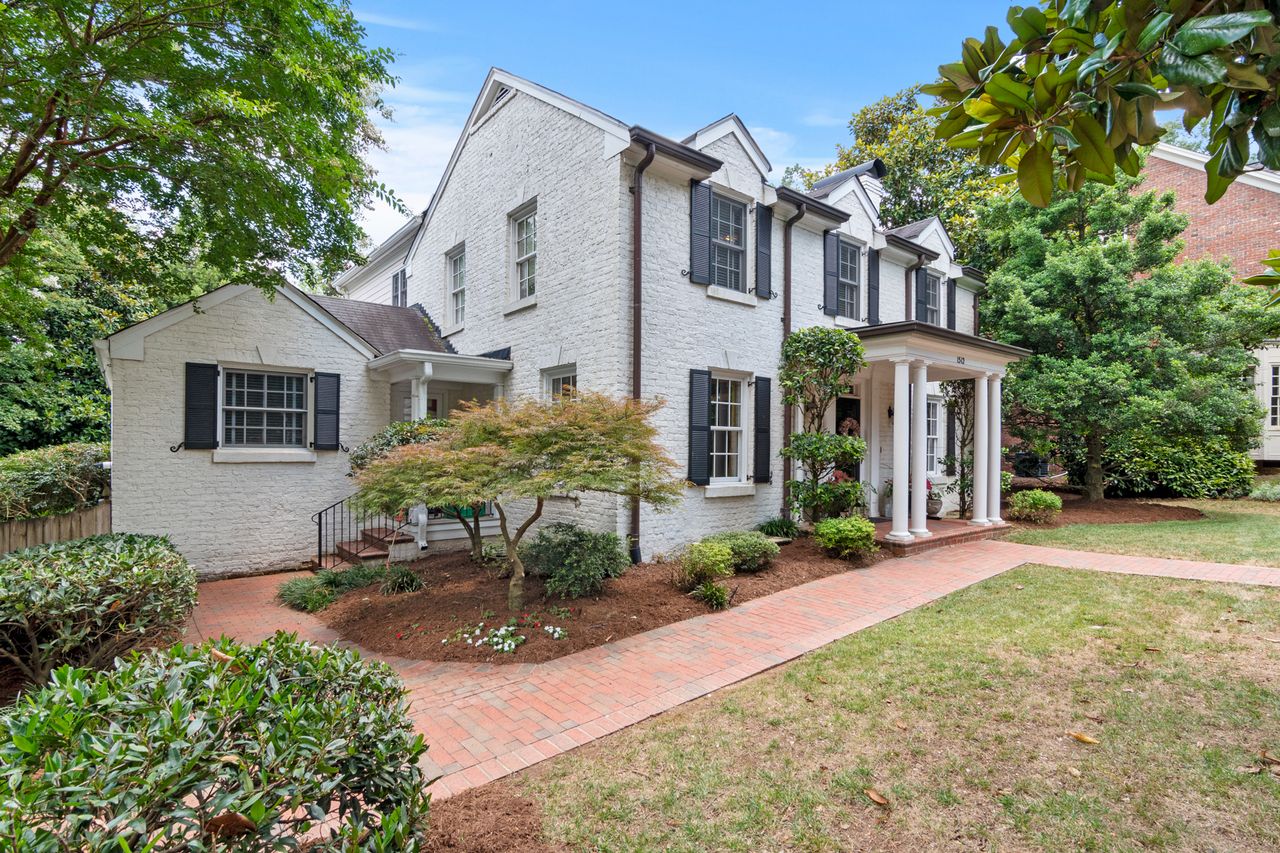 Elegant suburban house with brick facade and lush garden, perfect for serene living.